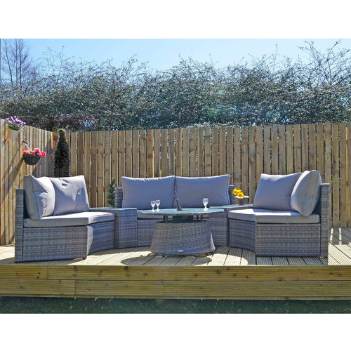 Grey rattan garden sofa set with circular coffee table and 3 sofas with side tables on decking with plants and flowers