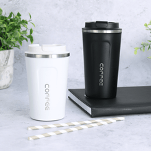 Load image into Gallery viewer, black and white coffee mugs in different sizes sitting on black book with foliage in the background and grey striped drinking straws in the foreground
