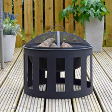 Load image into Gallery viewer, Black Vesta fire pit with steel mesh spark guard cover filled with logs ready for burning, sitting on decking area with plants and chair
