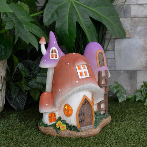 Light up solar power toadstool cottage garden decoration ornament on grass with plants and a stone wall