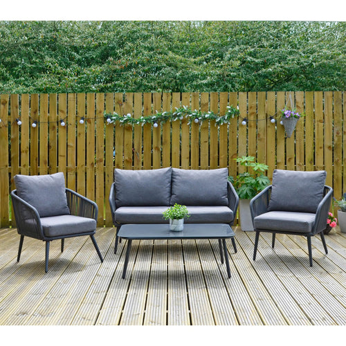 Black metal garden sofa set with string style arms, matching grey cushions and a black glass top coffee table, sitting outdoors on decking with plants and party lights