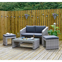 Load image into Gallery viewer, Grey rattan garden sofa set with 2 seater sofa, 2 ottoman stools and a glass topped coffee table, on decking with wine glasses magazine, plants and party lights
