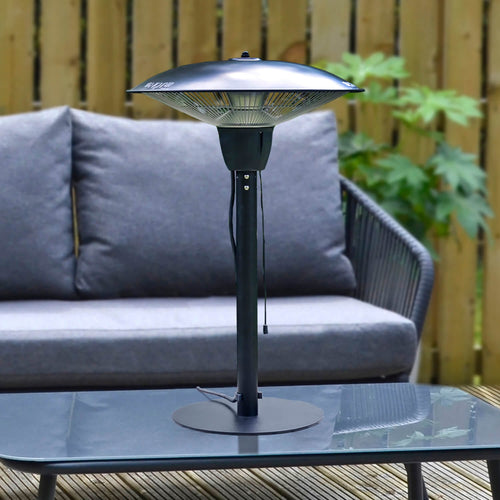 Electric patio heater, black steel with pull cord on/off switch on a glass topped coffee tale for outdoor entertaining