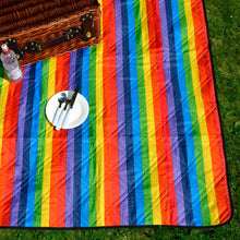 Load image into Gallery viewer, rainbow stripe picnic blanket on grass with picnic basket, water bottle and plate resting on top
