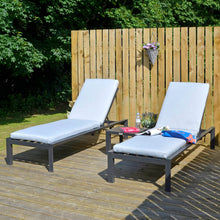 Load image into Gallery viewer, Set of 2 sun loungers and table with dark grey frames and light grey cushions, on garden decking with towel, water and plants
